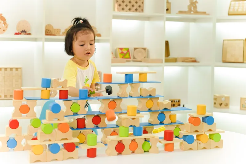 Preschooler developing fine motor skills with wooden construction toys for preschoolers