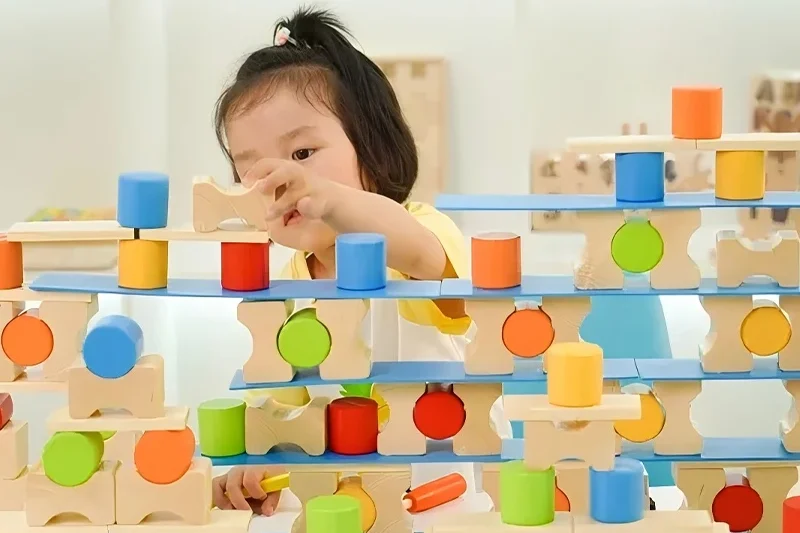 Building blocks for preschoolers - child creating tower with colorful wooden blocks