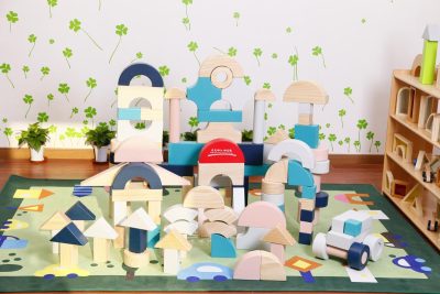 Large colorful wooden building blocks arranged as castles arches towers and a toy vehicle
