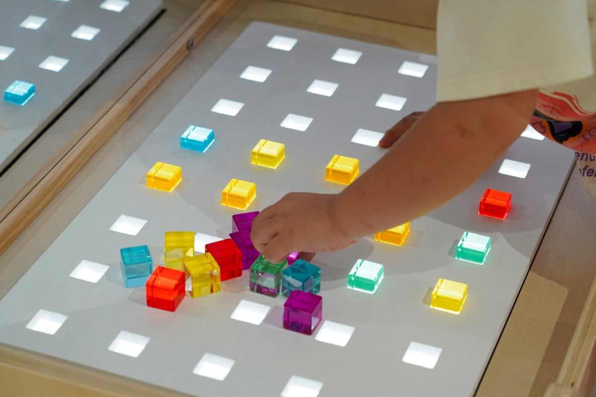 Sensory Light Table Guide: 15 Activities and Setup Tips 3 Preschool child arranging shapes during a sensory light table activity