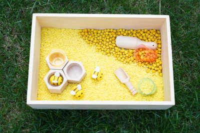 bee sensory bin with wooden tray rice bee figures and scooping accessories for preschool sensory play