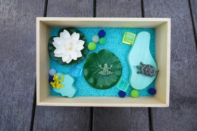 pond sensory bin with lotus flower lily pads frog turtle rice and wooden sensory tray