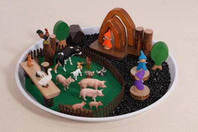 farm small world play set with assorted farm animal figures, wooden farm scenery and a circular scene tray