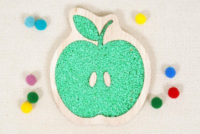 apple sensory tray made from rubberwood with green rice and colored loose parts