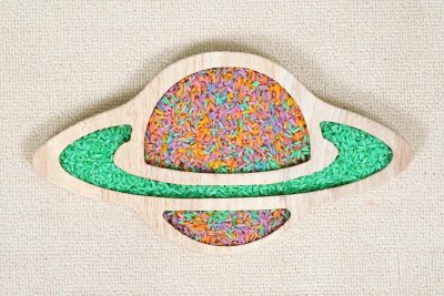 wooden Saturn sensory tray with colorful rice filling the planet, surrounding rings and lower compartment